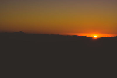 Scenic view of silhouette mountains against orange sky