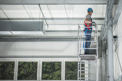 Man working while standing on scaffolding in building