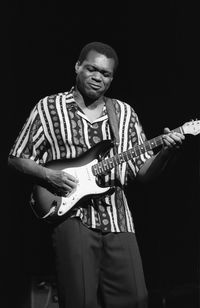 Full length of man playing guitar against black background