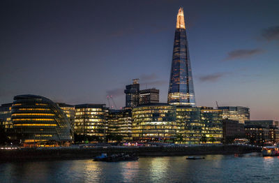 Illuminated skyline of london by river thames at night