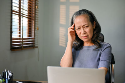 Portrait of young woman using laptop at home