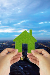 Cropped image of woman holding jigsaw piece against city