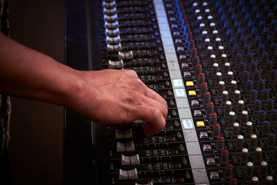 Cropped hand using sound mixer at studio