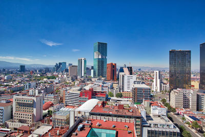 Modern buildings in city against blue sky