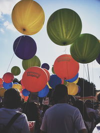 Rear view of people with umbrellas against sky