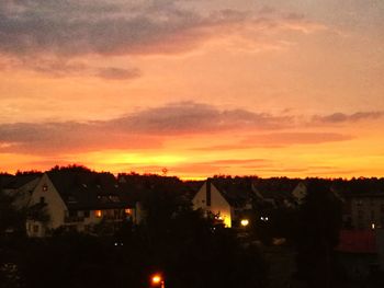 Silhouette houses in town against sky during sunset