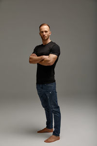 Portrait of young man standing against gray background