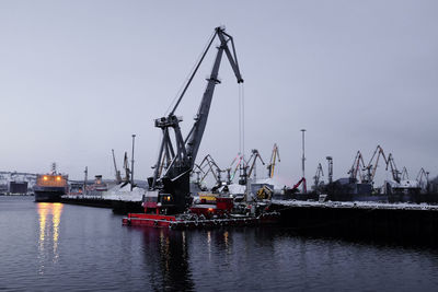 Cranes at harbor against clear sky