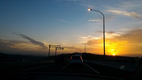 Car on highway against sky during sunset