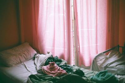 High angle view of messy blankets on bed by window curtain at home