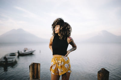 Young woman standing in sea against sky