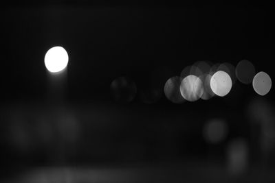 Defocused image of illuminated lights against sky at night