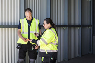 Warehouse workers discussing over digital tablet while standing at entrance