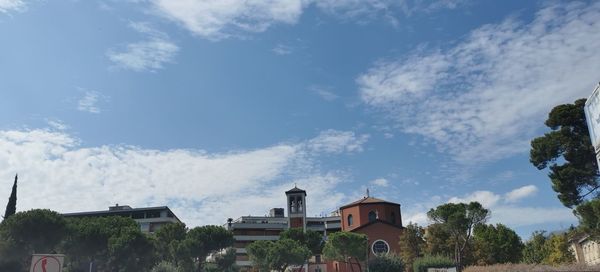 Low angle view of trees and buildings against sky