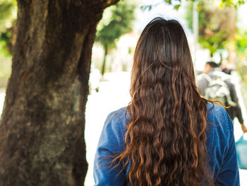 Rear view of woman with tree trunk