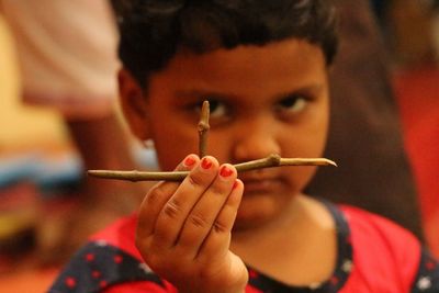 Close-up portrait of girl holding sticks