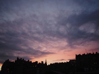 Silhouette of city against cloudy sky