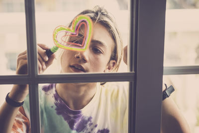 Portrait of young woman looking through window