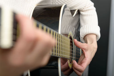 Midsection of person playing acoustic guitar