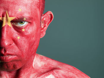 Close-up portrait of man with chinese flag body paint against gray background