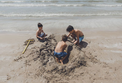High angle view of shirtless brothers playing on shore at beach