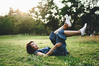 Woman lying down on field against trees