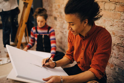 High angle view of artist painting on canvas with friends in background