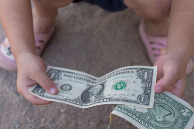 Low section of baby holding paper currencies