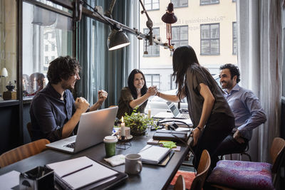 Happy businesswomen holding hands in meeting at creative office