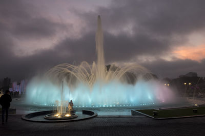 Illuminated fountain in city against sky at night