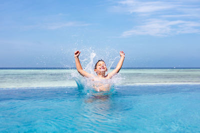 Funny kid jumping into a infinity swimming pool