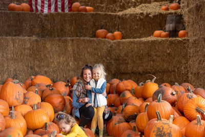 Smiling mother and daughter standing amidst pumpkin