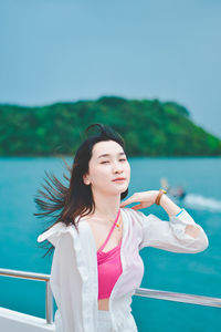 Portrait of young woman standing against clear sky