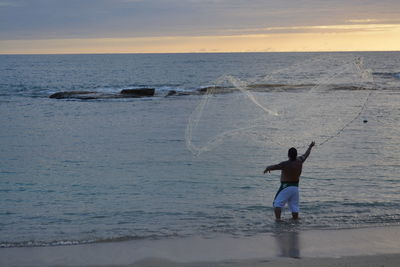 Rear view of man standing on beach against sky