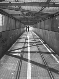 Rear view of man and woman walking on covered footbridge