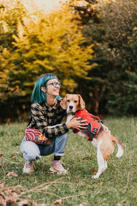 Portrait of young woman with dog on grassy field