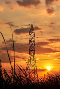 Low angle view of silhouette electricity pylon against sky during sunset