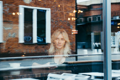 Portrait of woman looking through window