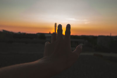 Close-up of silhouette hand against sky during sunset