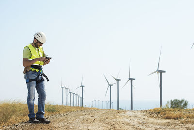 Engineer using tablet computer at wind farm against sky