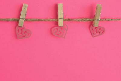 Close-up of heart shape hanging on pink background