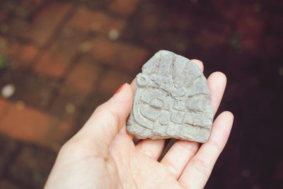 Close-up of hand holding stone with carving