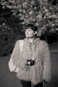 Woman wearing fur coat while looking away outdoors