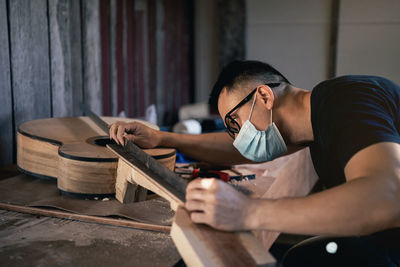 Man working over guitar on table