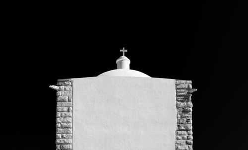 Religious cross over building against sky at night