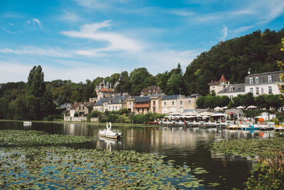 Houses by lake against sky in city