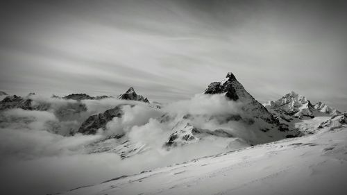 Snow covered mountain against cloudy sky