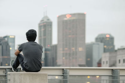 Rear view of man looking at city buildings