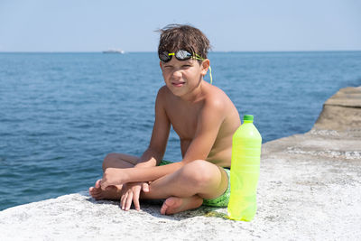 Portrait of boy sitting against sea