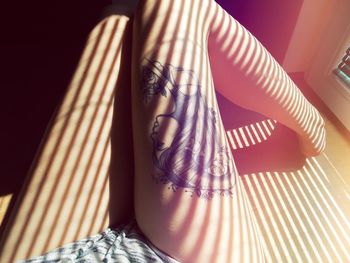 Low section of woman with tattoo on leg at home